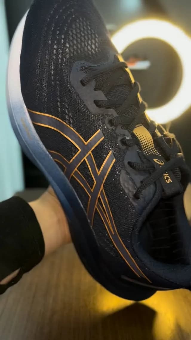 Tênis Asics na mão, na frente do ring light da loja